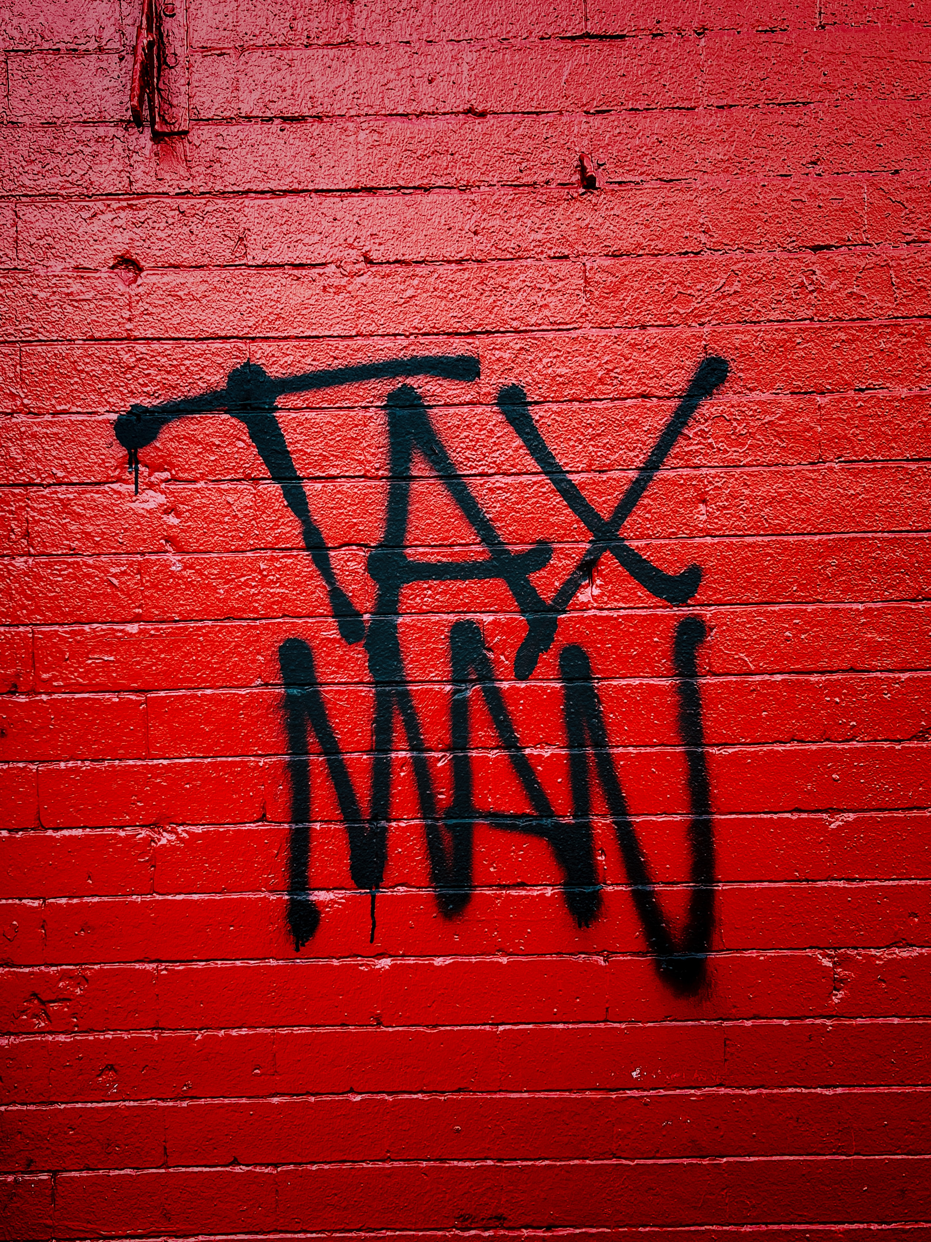 Tax Man painted in black on a red brick wall